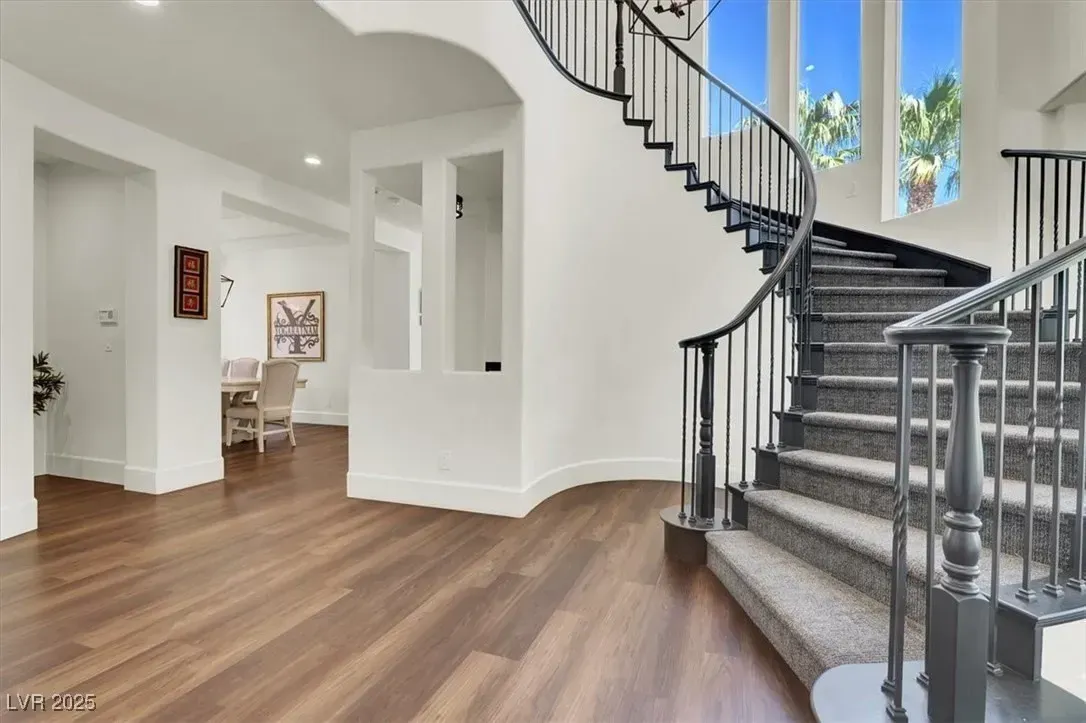 Bright foyer with wood floors and a curved staircase by large windows
