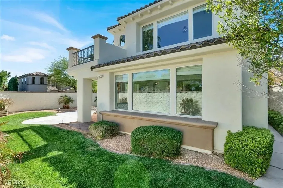 Modern two-story house with large windows, white stucco exterior, and a landscaped green lawn.