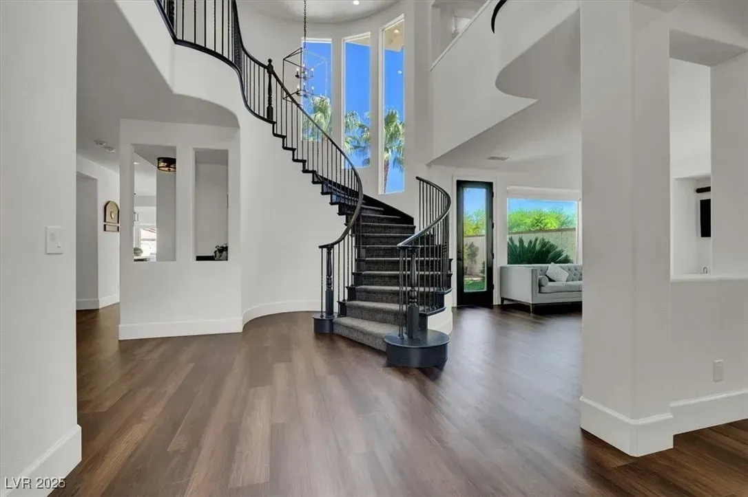 Bright modern foyer with dark spiral staircase, wood floors, and large windows.