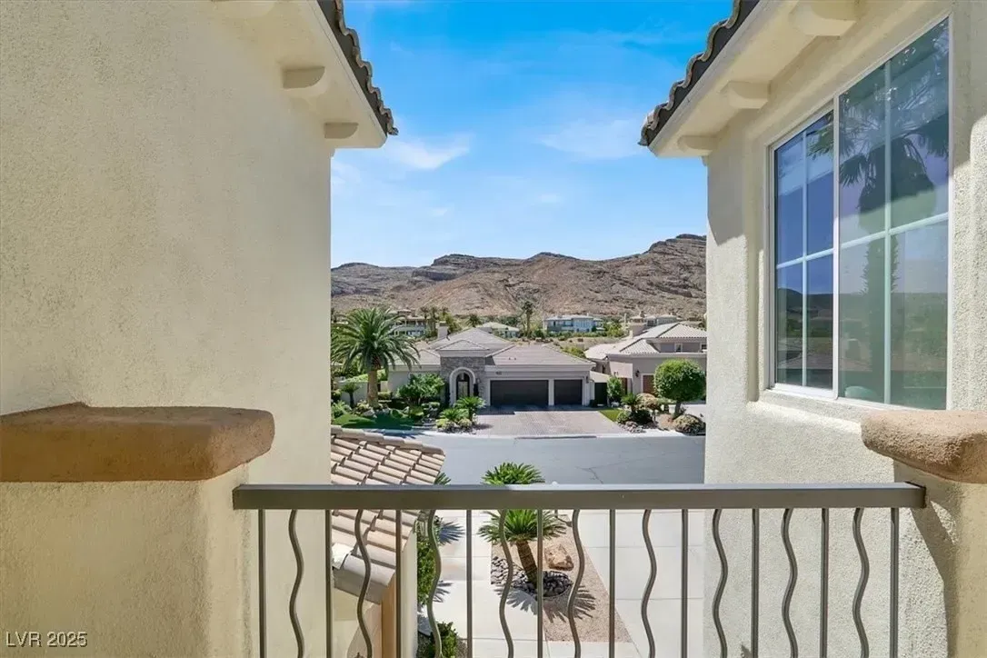 View from a balcony over a sunny suburban street, with hills in the distance