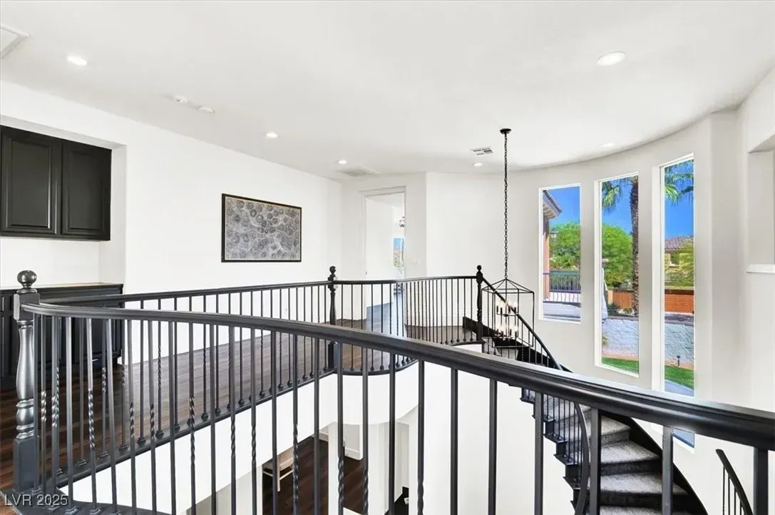 Bright upstairs landing with black railings, staircase, and large windows overlooking outdoors