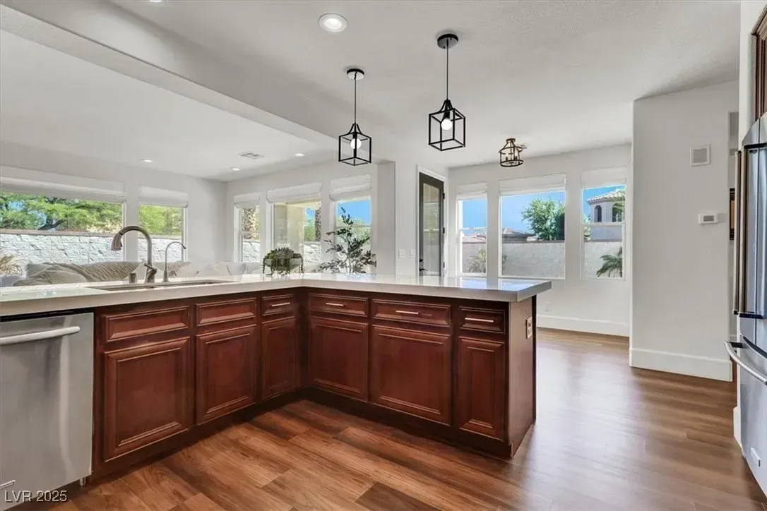 Bright kitchen with dark wood island, white countertops, hanging lights, and large windows