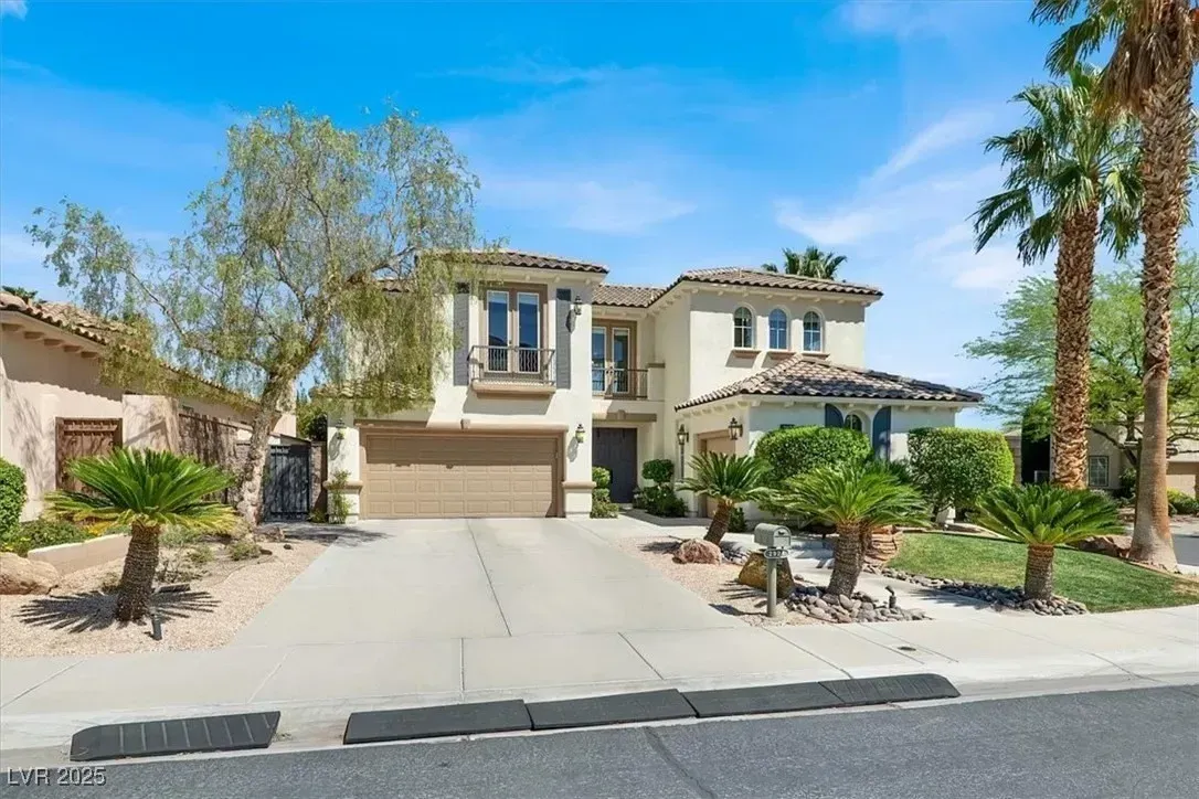 Modern two-story stucco house with a wide driveway, palm trees, and desert landscaping