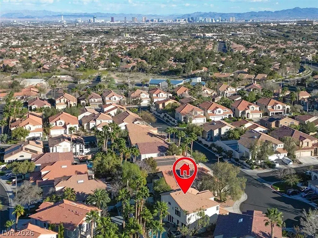 Aerial view of a suburban neighborhood with a red location pin marking a house near the center.