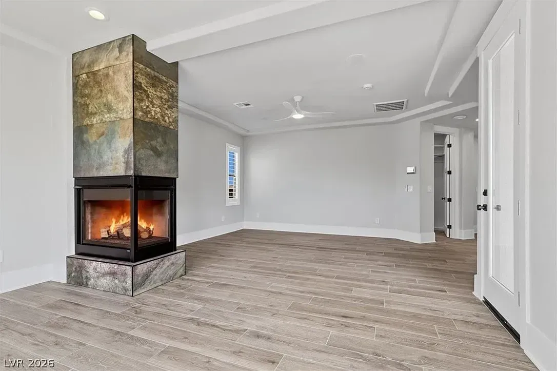 Modern empty living room with a corner fireplace and light gray walls and flooring