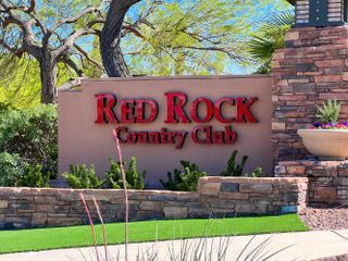 Red Rock Country Club sign on a stone wall with desert landscaping and trees
