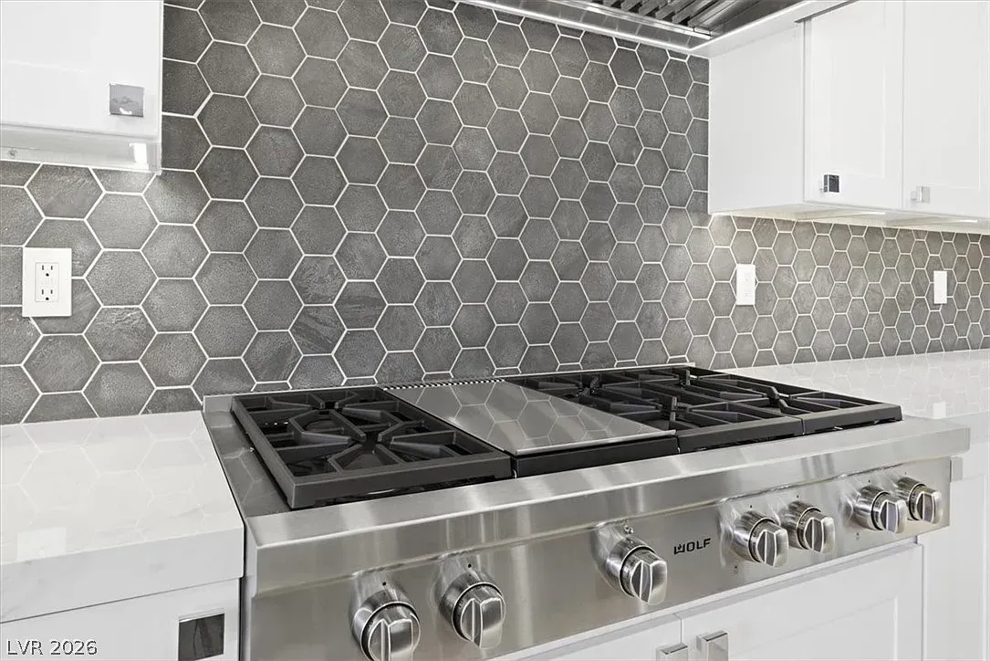 Modern kitchen with stainless steel gas range and gray hexagon tile backsplash