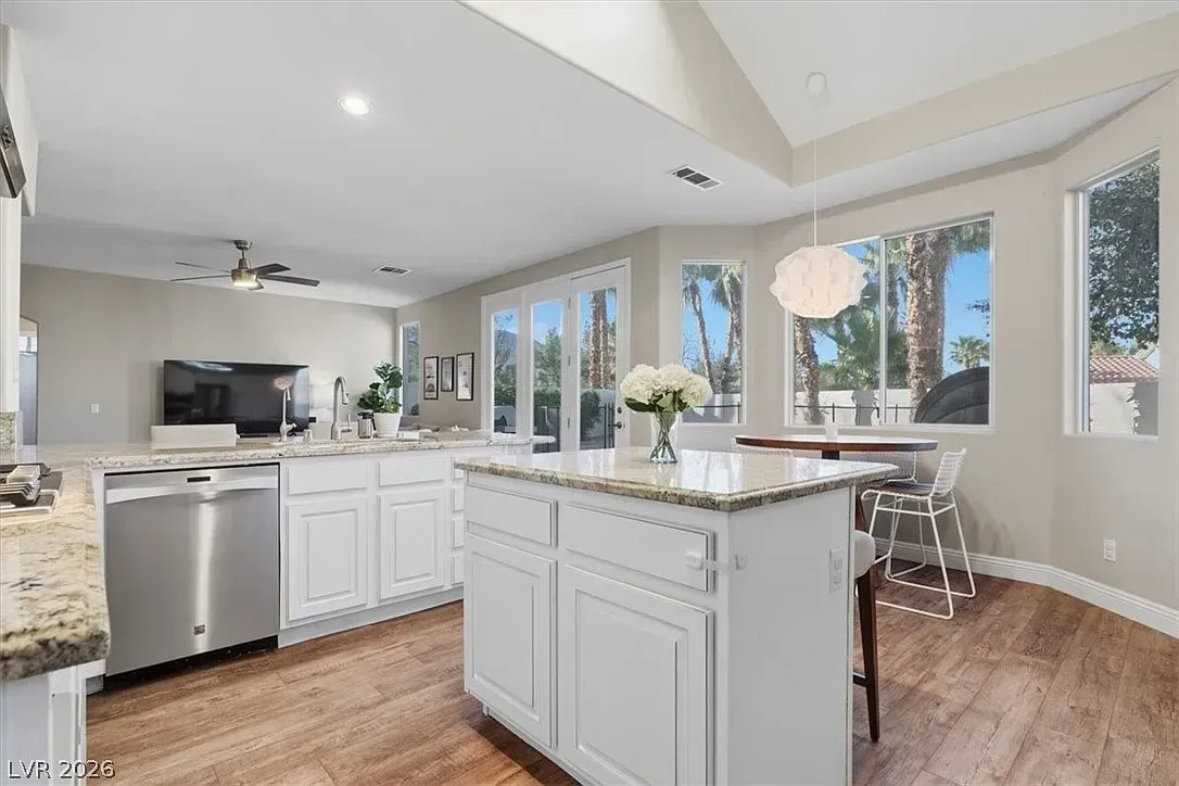Bright modern kitchen with white cabinets, granite island, stainless appliances, and large windows