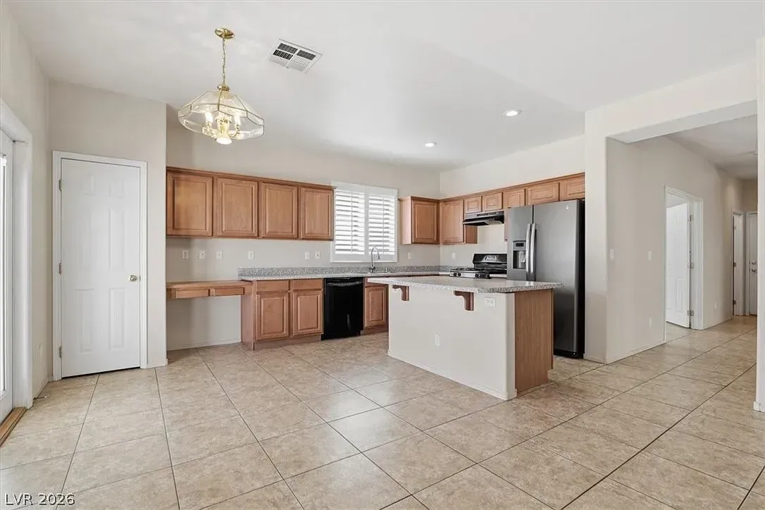 Bright kitchen with wood cabinets, stainless steel appliances, white island, and tiled floor