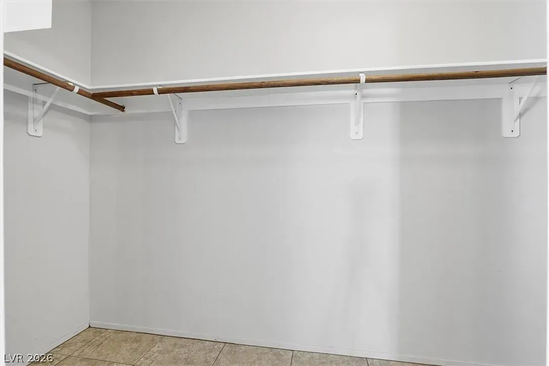 Empty walk-in closet with white walls, wire shelf, and beige carpet.