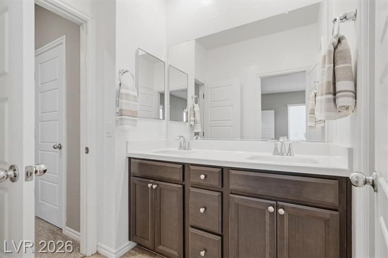 Bright bathroom vanity with dark wood cabinets, double mirrors, and white countertops in a neutral interior.