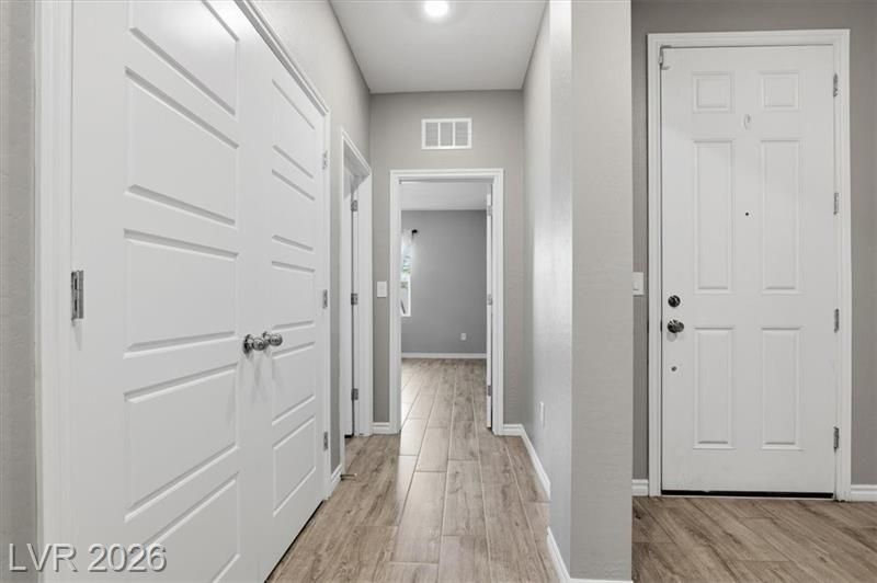 Modern hallway with gray walls, wood-look floors, white doors, and recessed ceiling lights