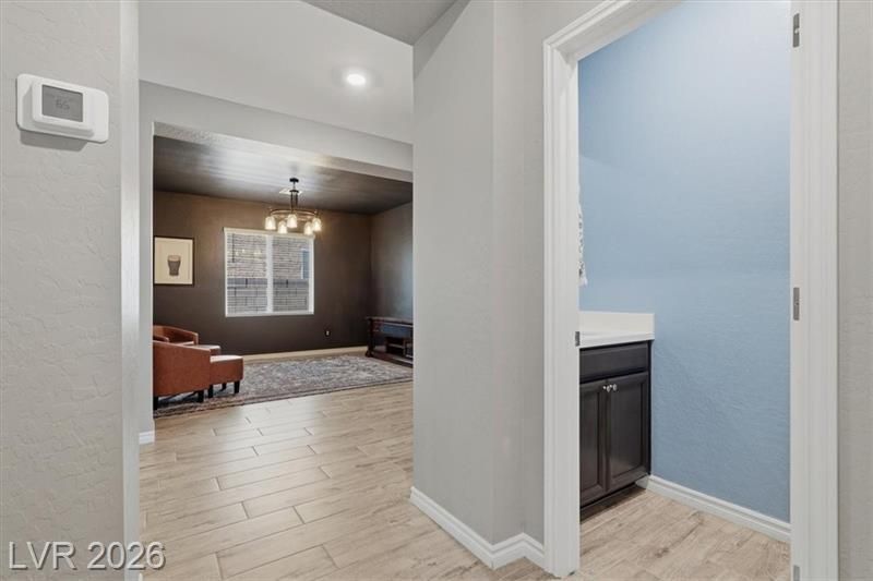 Hallway view into a living room and a blue-painted bathroom with a vanity.