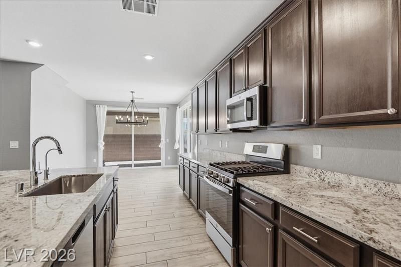 Modern kitchen with dark wood cabinets, granite counters, stainless appliances, and a view of the dining area