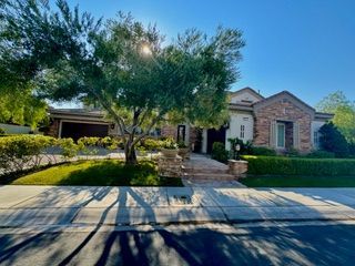 Suburban home with a front yard, stone walkway, and a tree in bright sunlight