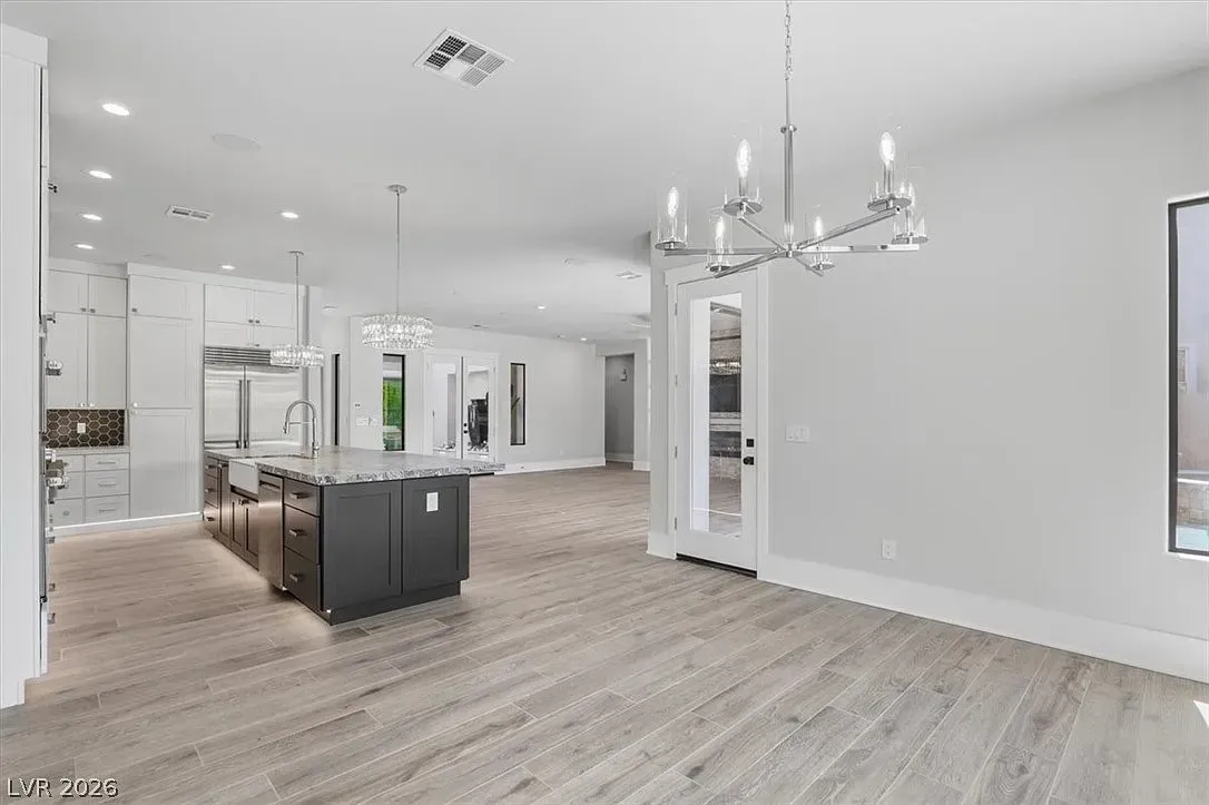 Bright modern kitchen and dining area with island, white walls, and light wood flooring