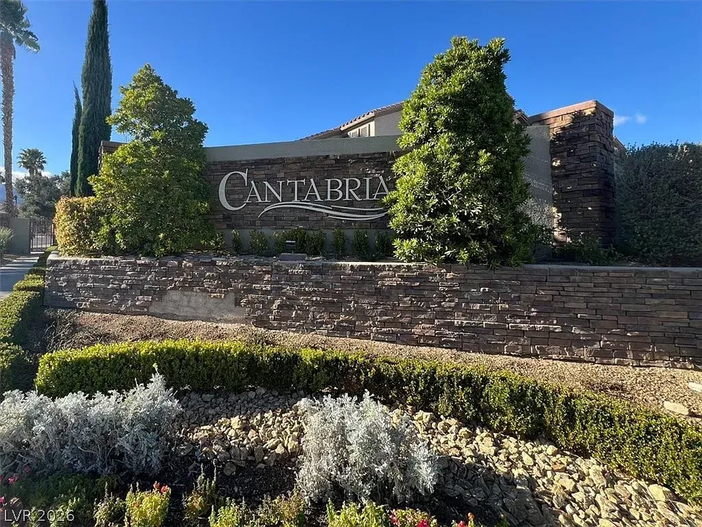 Stone entrance sign for Canterra with landscaped shrubs and trees under a clear blue sky