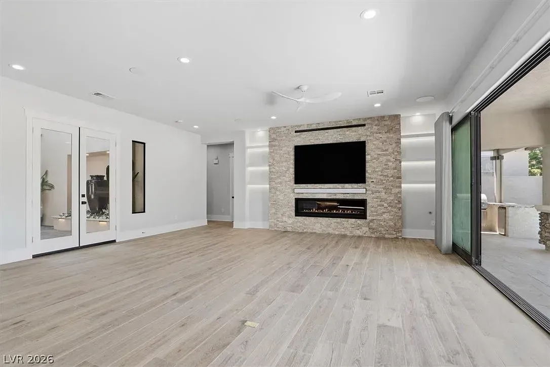 Bright modern living room with fireplace, white walls, light wood floors, and large sliding glass doors