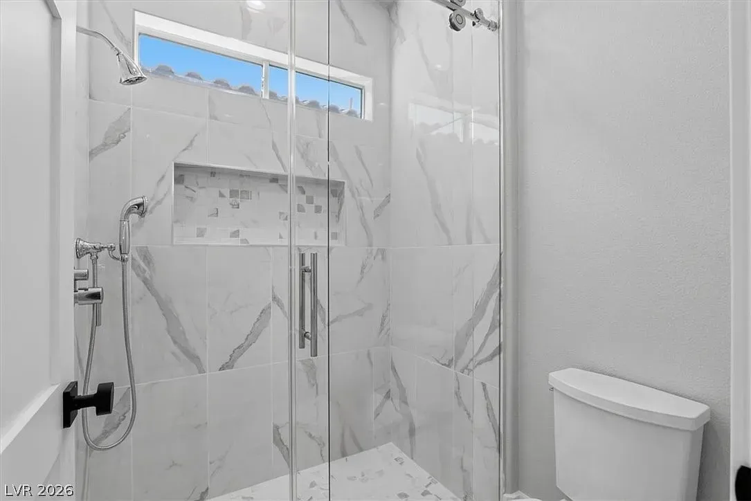 Modern white shower with glass door and chrome fixtures in a bathroom