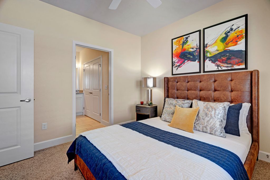 A bedroom with a large bed and two paintings on the wall.