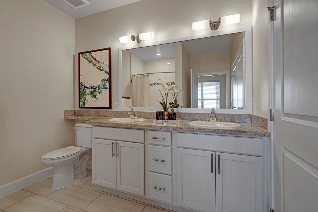 A bathroom with two sinks , a toilet , and a large mirror.
