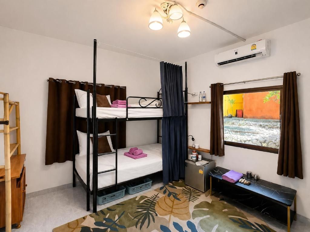 Small bedroom with bunk bed, window bench, ceiling light, and blue curtains.