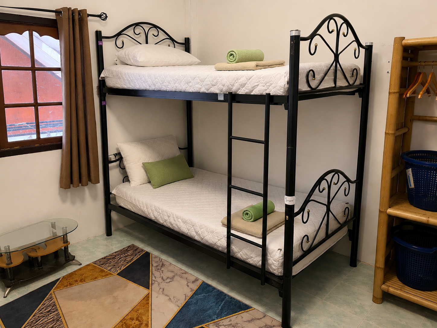 Small bedroom with black metal bunk bed, white walls, window, and beige curtains