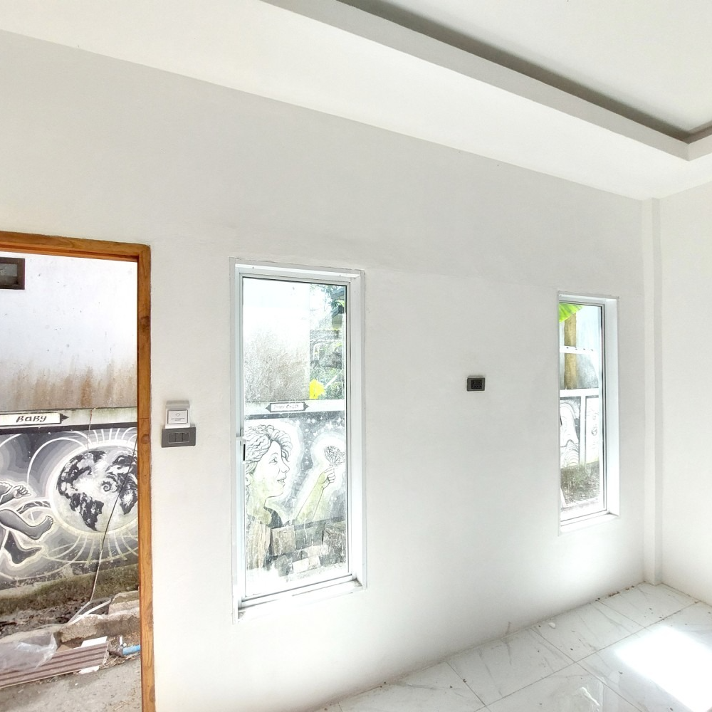 Empty white room with tiled floor, three narrow windows, and a door opening to patterned outdoor wall.