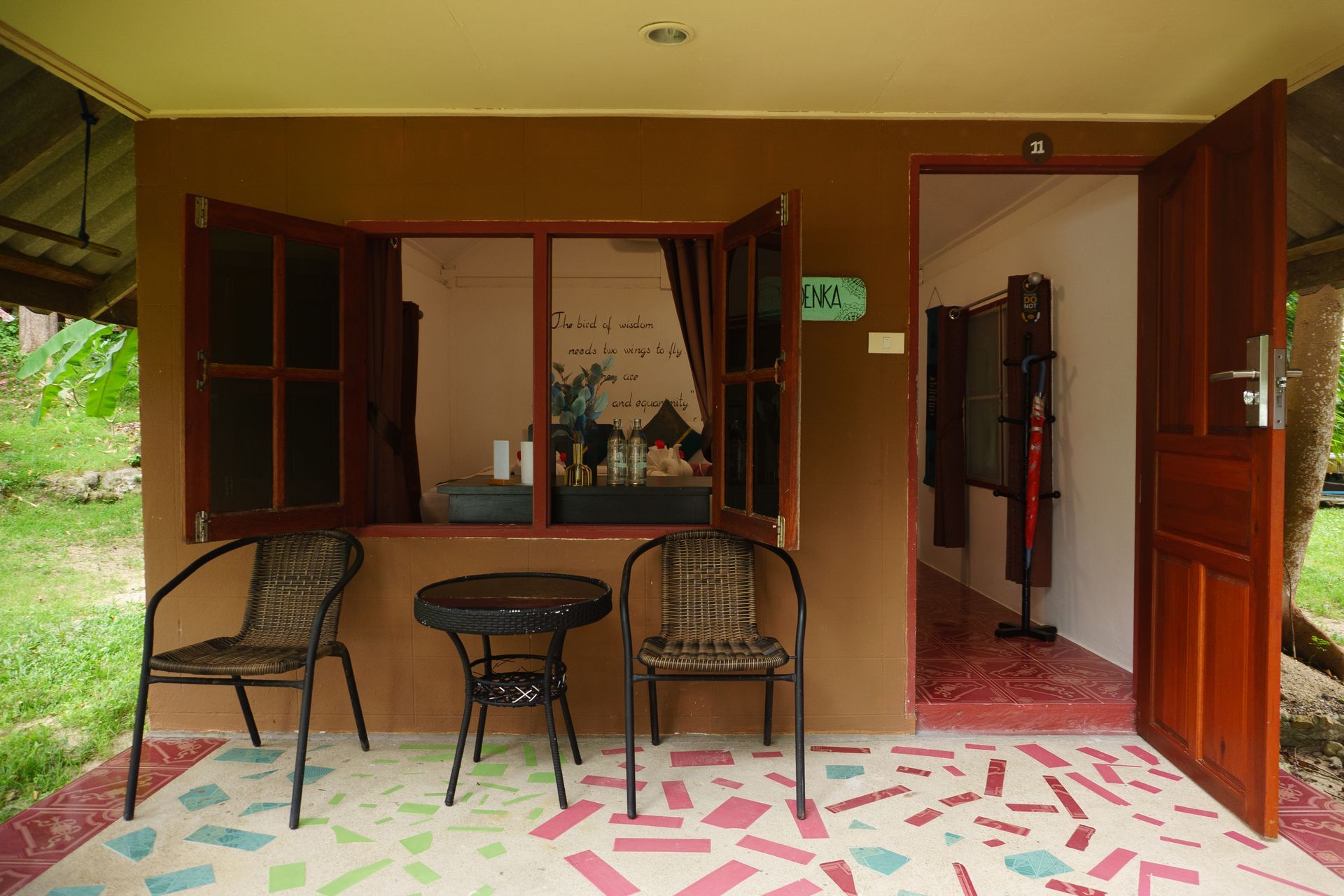 Open patio with two chairs, small table, and open wooden doors leading into a tiled interior.