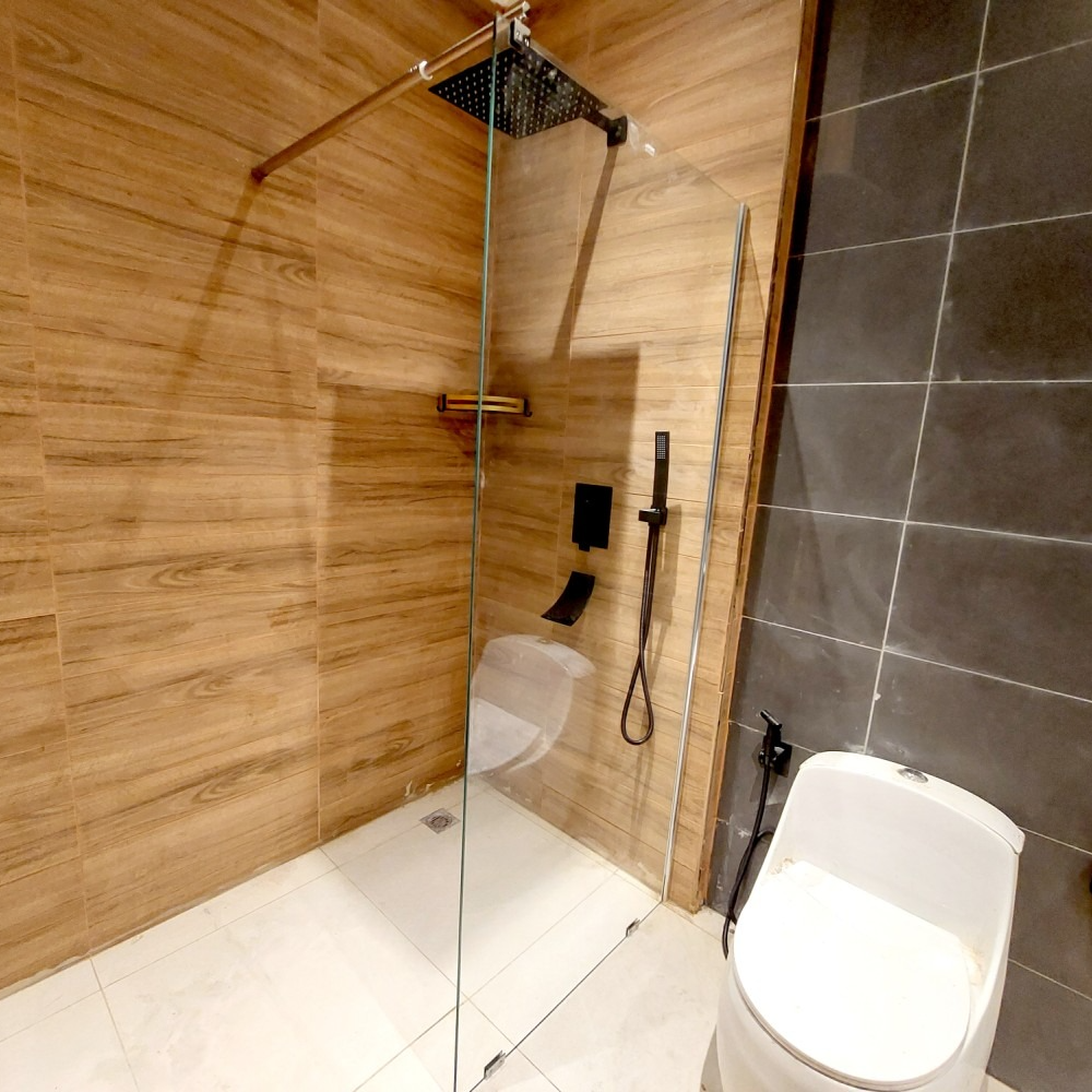Modern bathroom with glass shower, wood and gray tiled walls, and a white toilet