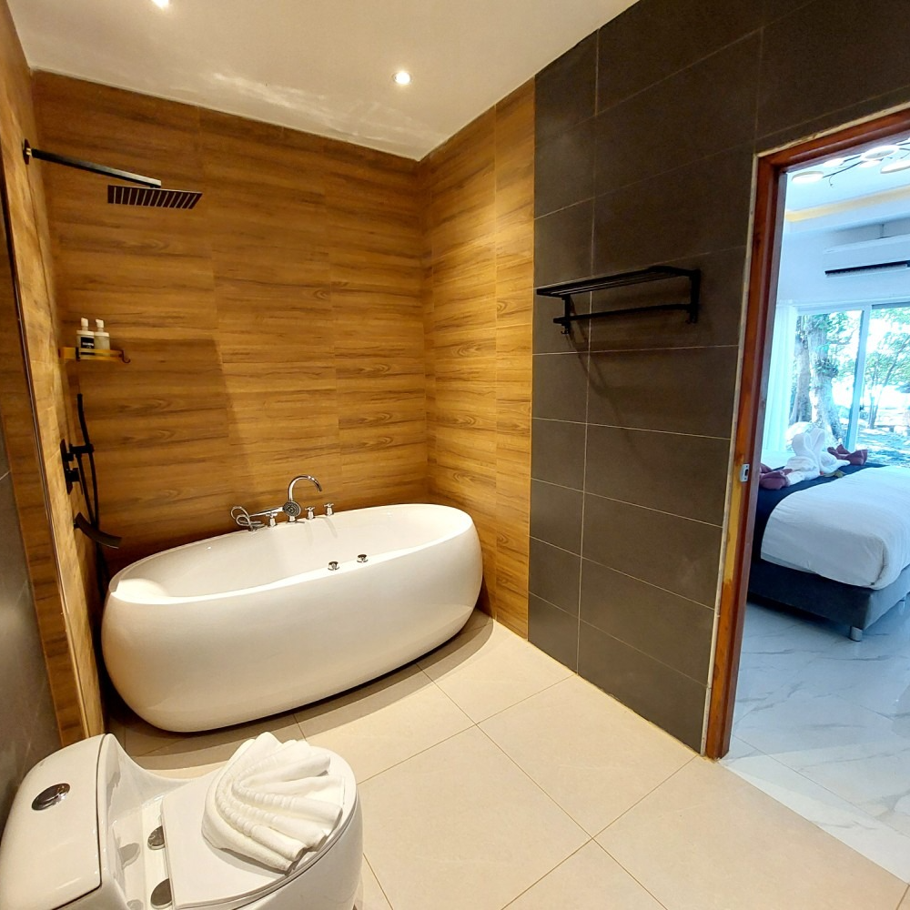 Modern bathroom with a freestanding tub, tiled walls, and an open doorway to a bedroom