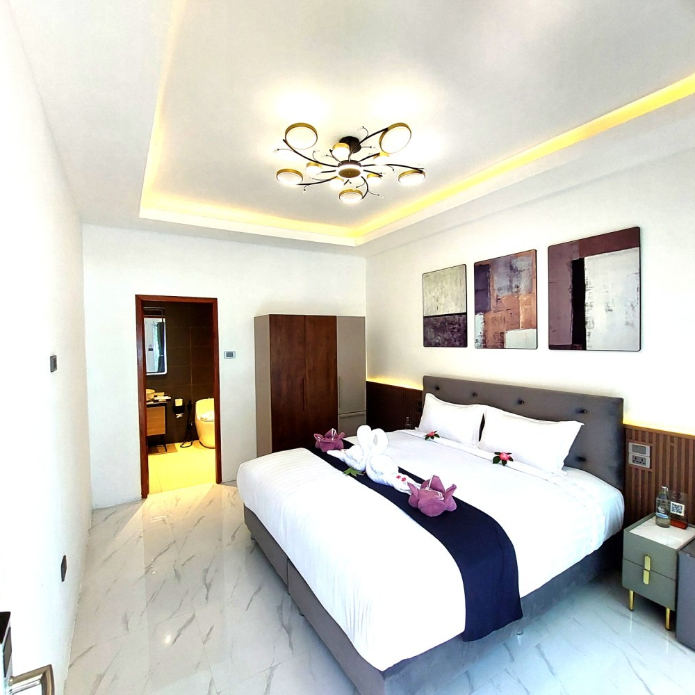 Modern bedroom with a large bed, wall art, ceiling light, and doorway to an adjoining room