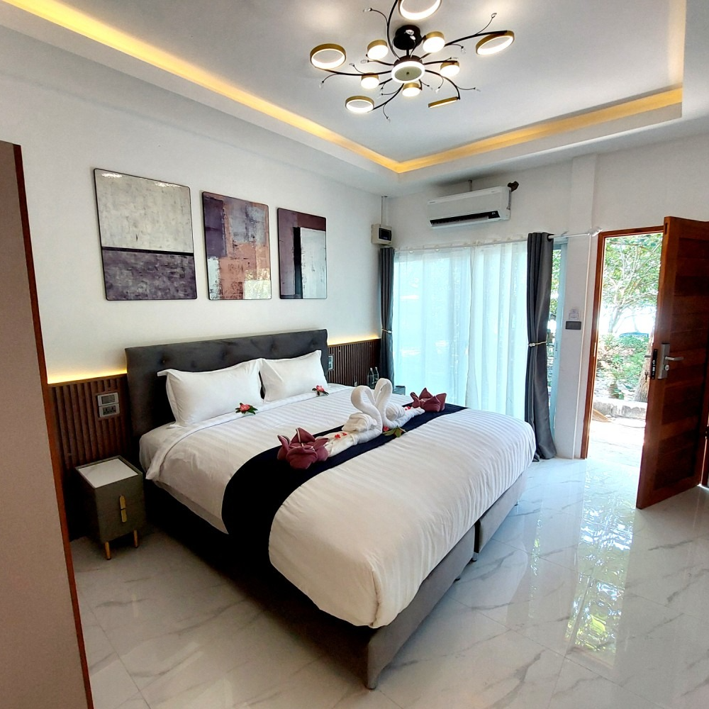 Modern bedroom with white bed, dark accents, wall art, ceiling light, and open balcony doors