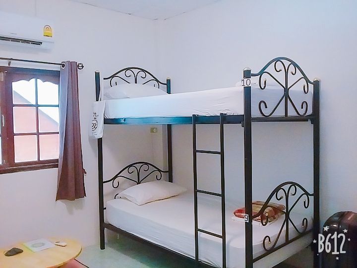 Bunk beds in a white-walled room with a window, air conditioning, and a small table.