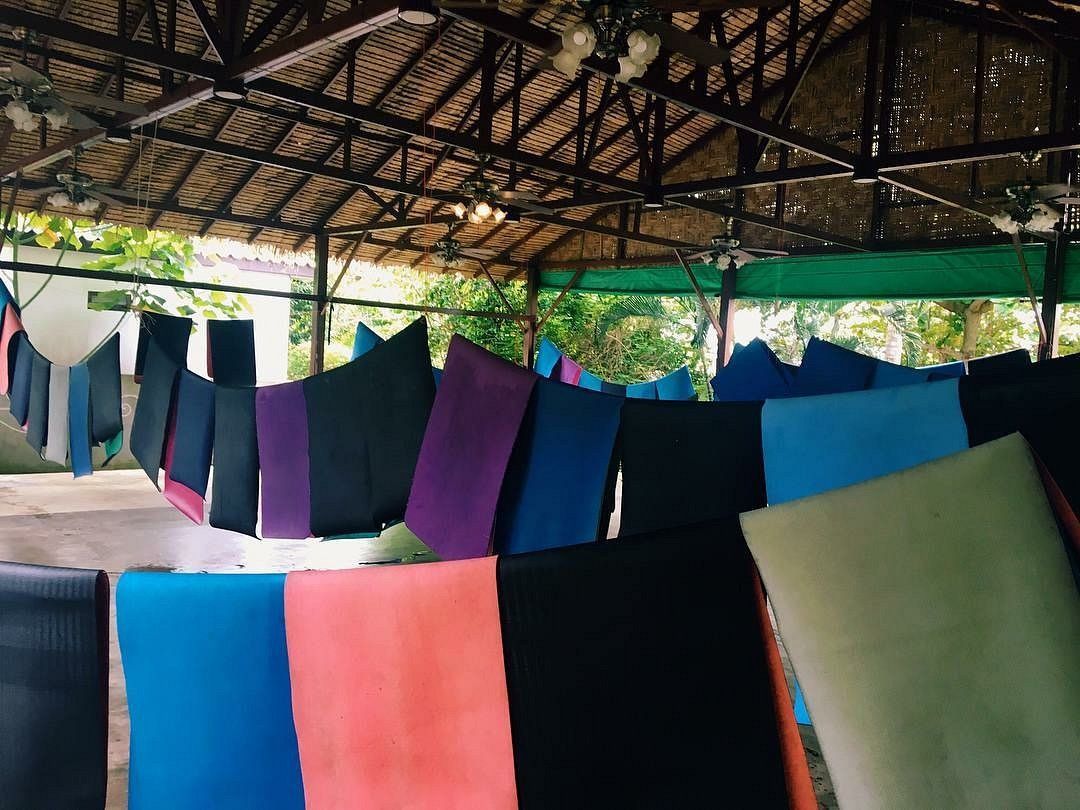 Colorful fabric panels hanging to dry under a covered outdoor shelter