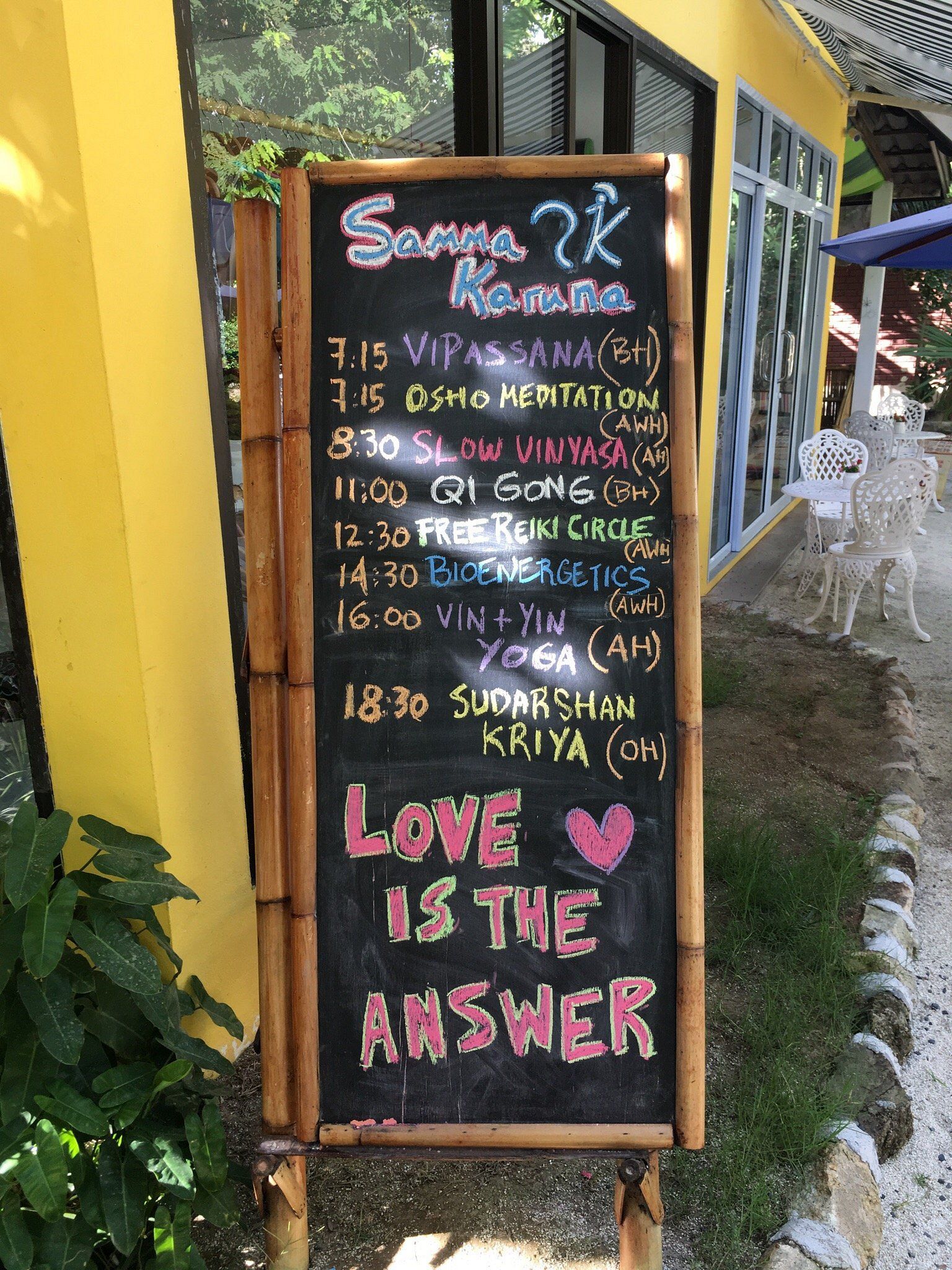 A sidewalk chalkboard menu outside a café with colorful text and “LOVE IS THE ANSWER” at the bottom.