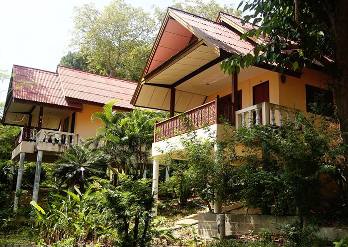 Tropical hillside bungalows with red roofs and balconies amid lush green vegetation
