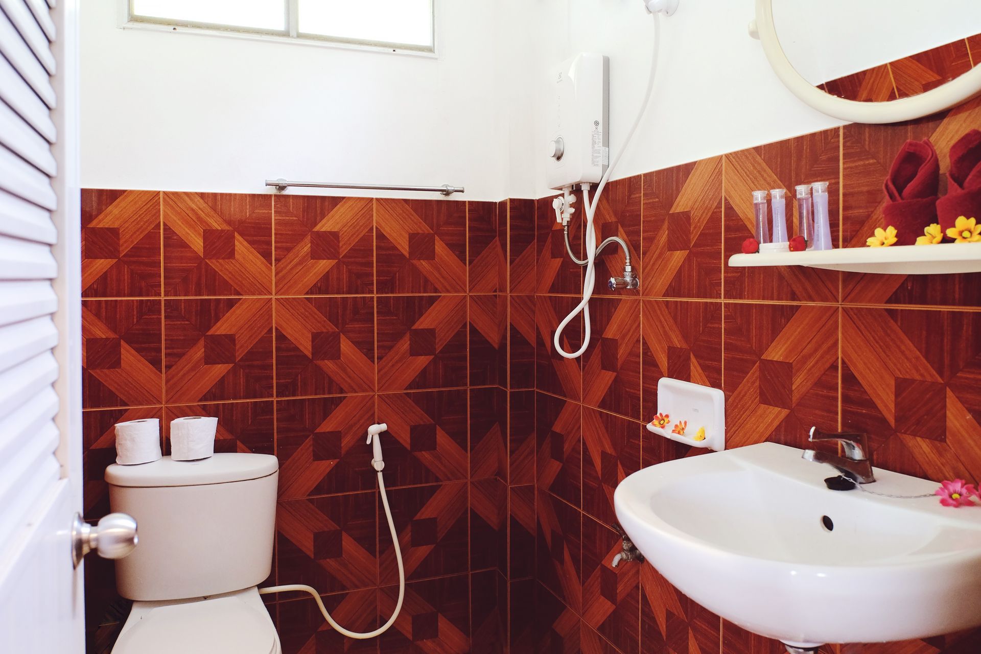 Bathroom with brown patterned tile walls, white toilet, sink, and towels.