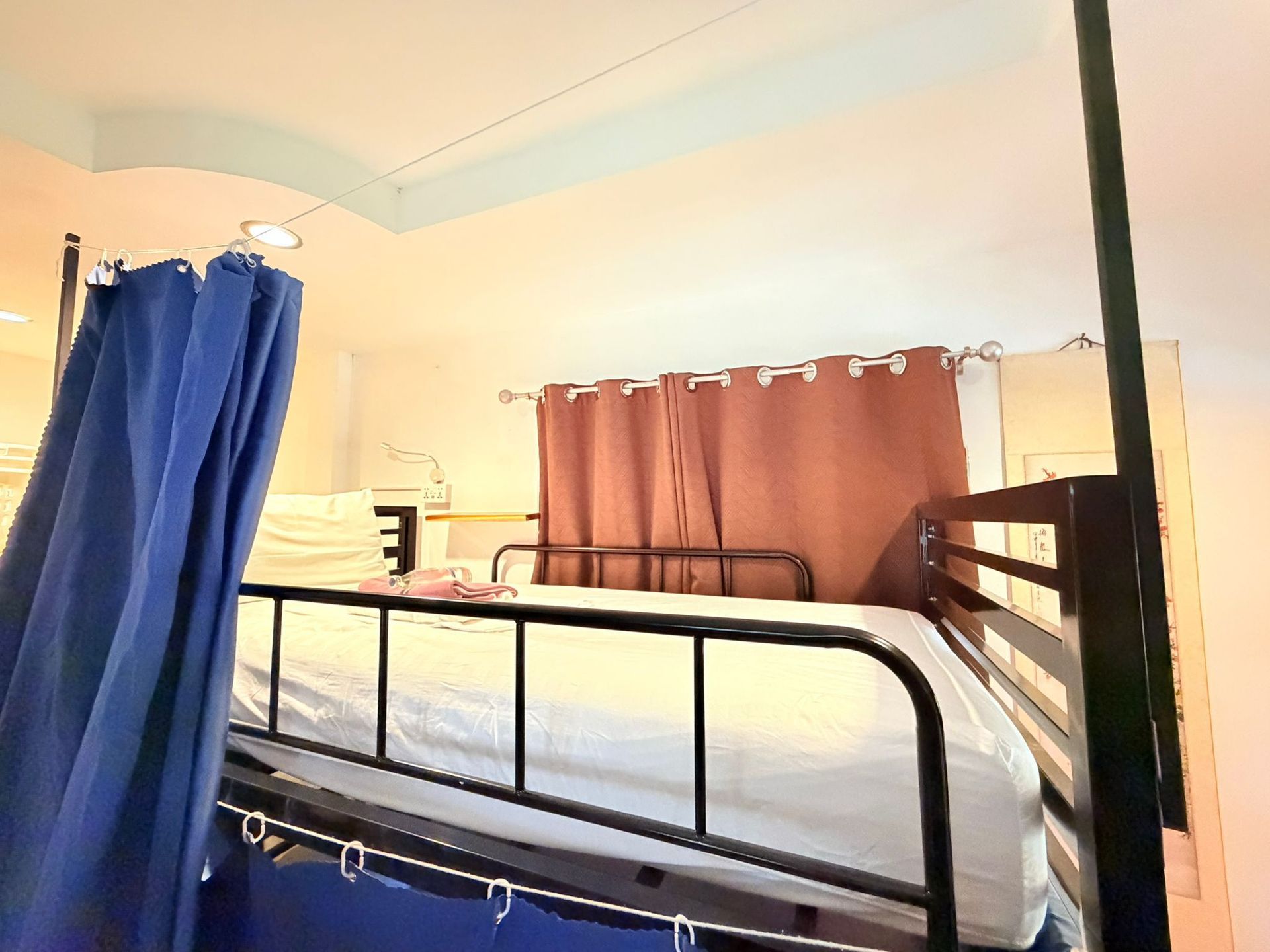 Blue-curtained bunk bed with white bedding in a softly lit bedroom