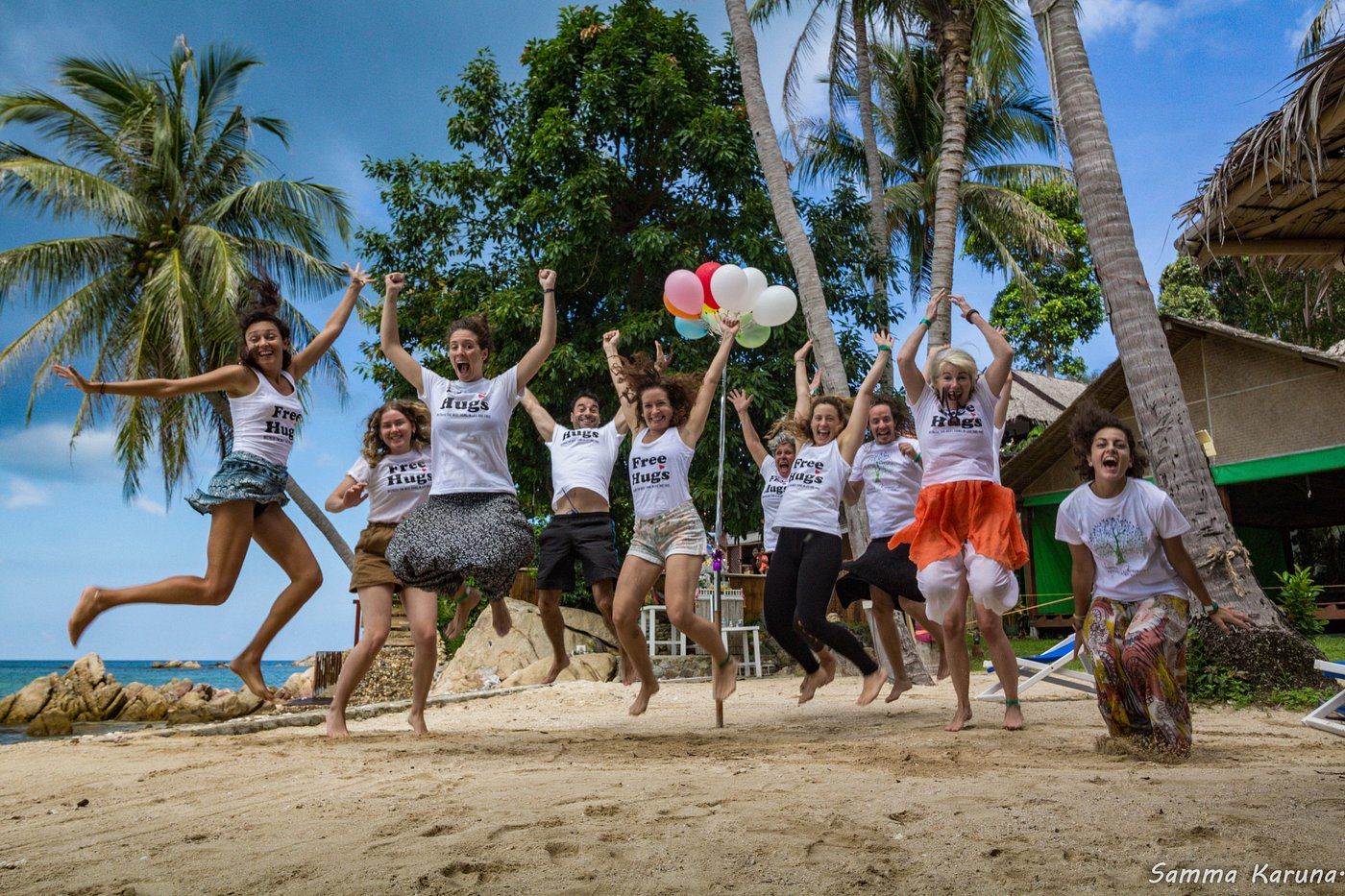 Group of children jumping on a tropical beach with palm trees and colorful balloons