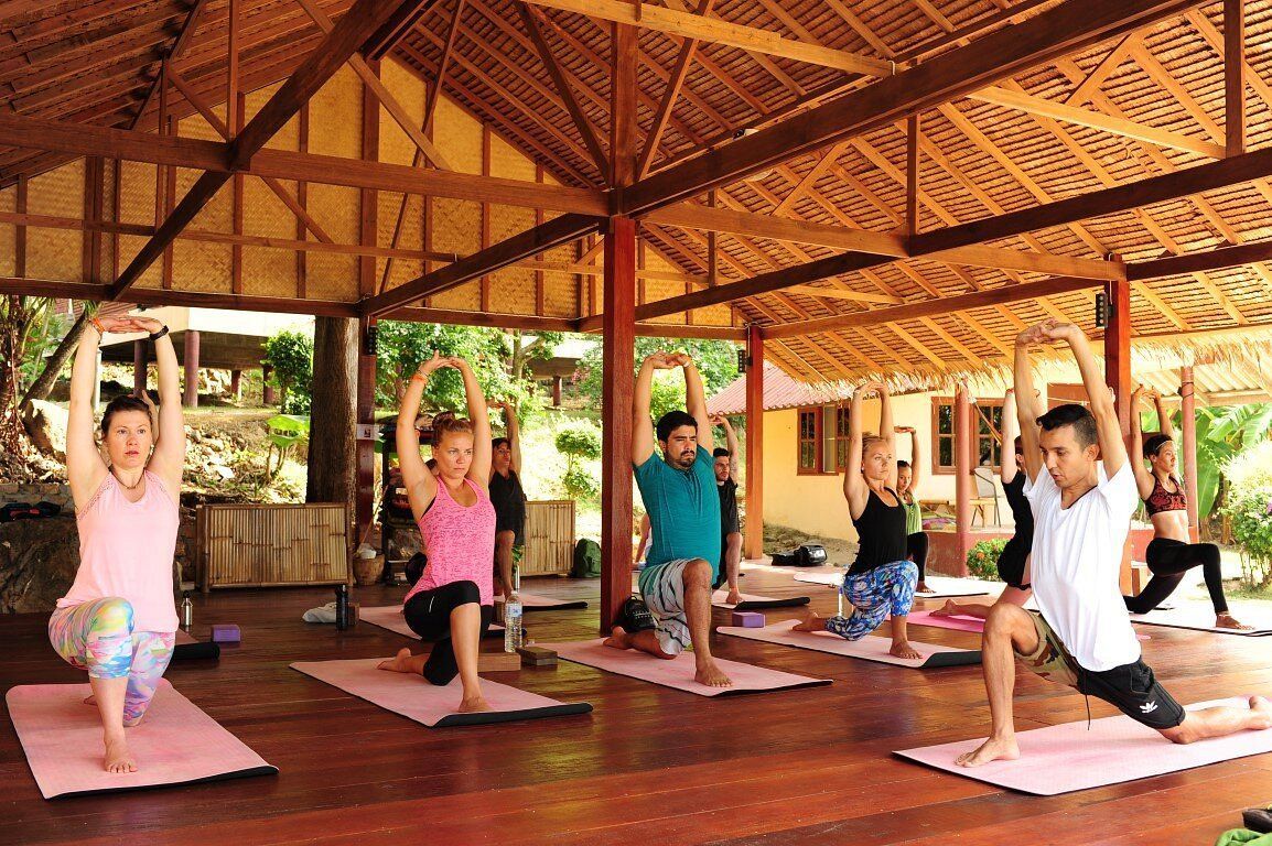 Group doing yoga on mats in an open wooden pavilion with natural light