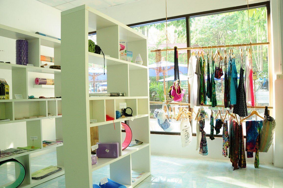 Bright boutique interior with white shelves and a window display of colorful hanging clothing