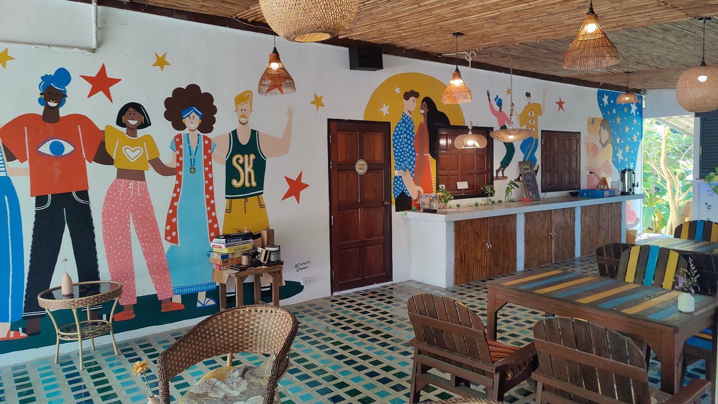 Colorful mural in a cozy café with wooden tables, patterned floor tiles, and a counter at the back