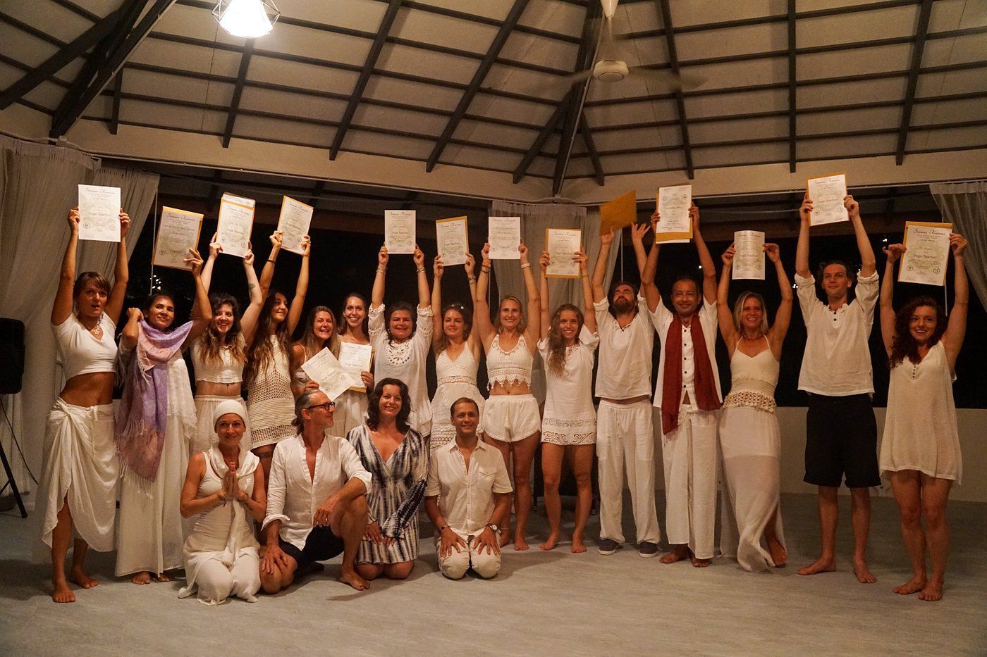 Group of people in white clothes standing indoors, holding up signs in a circular hall.