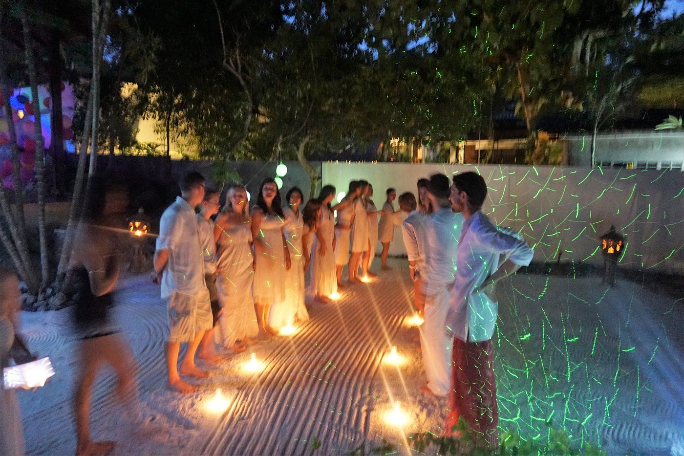 People standing around glowing ground lights at night in an outdoor courtyard