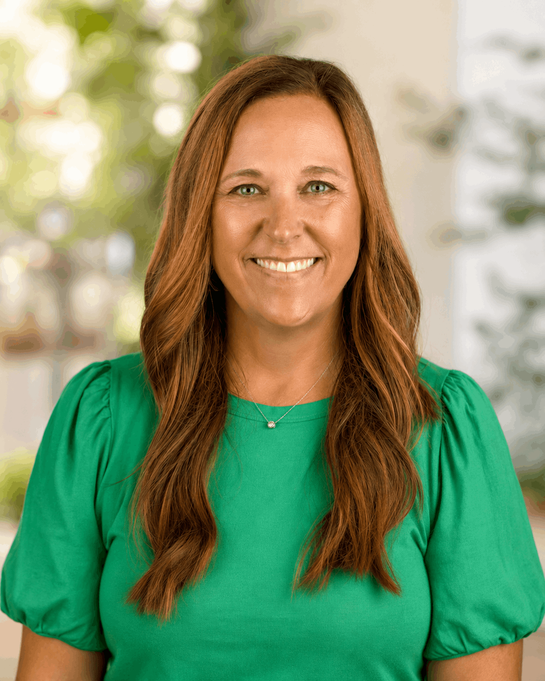 Smiling woman in a green top against a softly blurred indoor background