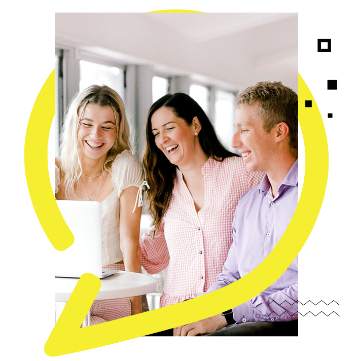 two women and a man laughing while looking at the laptop