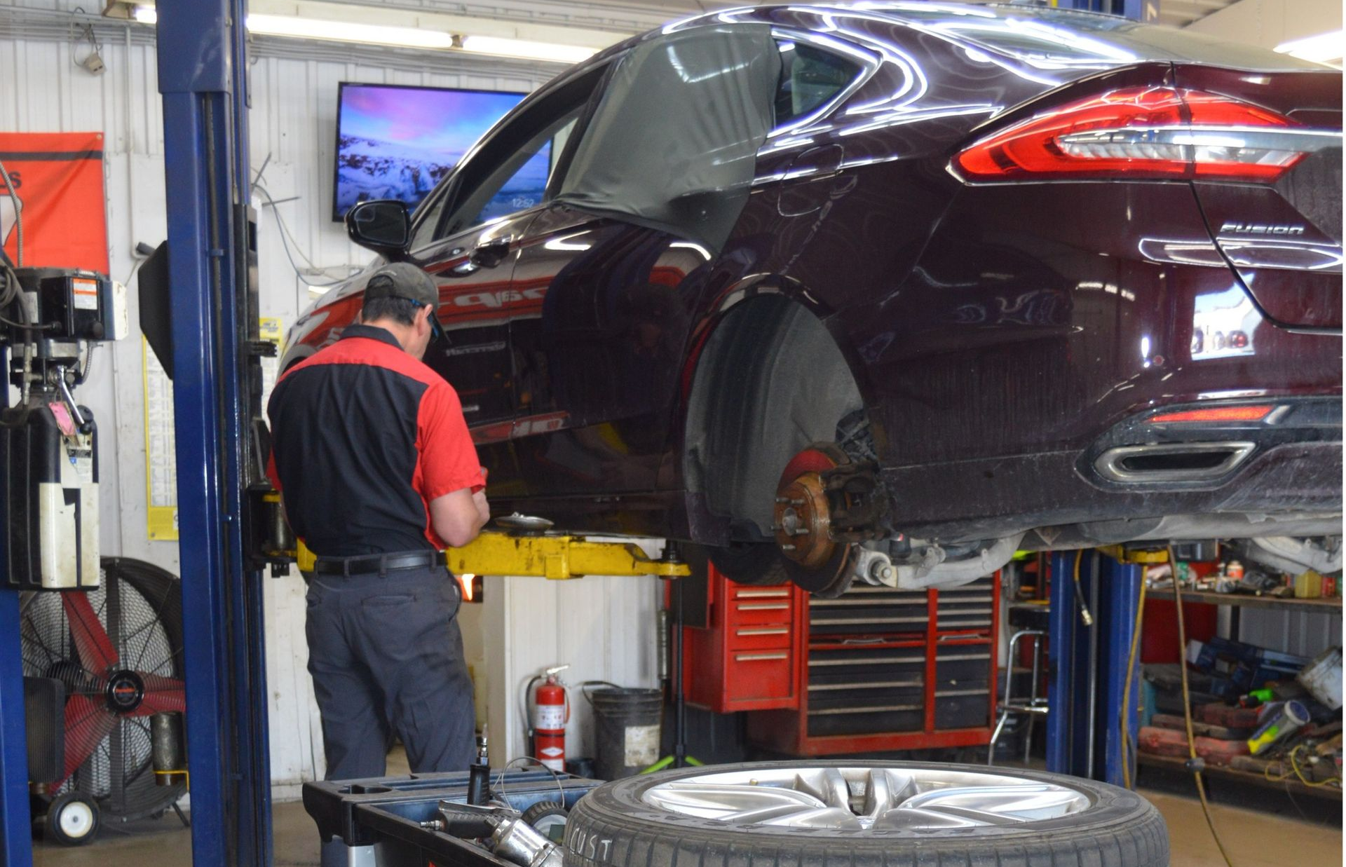 Technician Performing Undercar Inspection On Lift | Dial A Tire Automotive Service Center