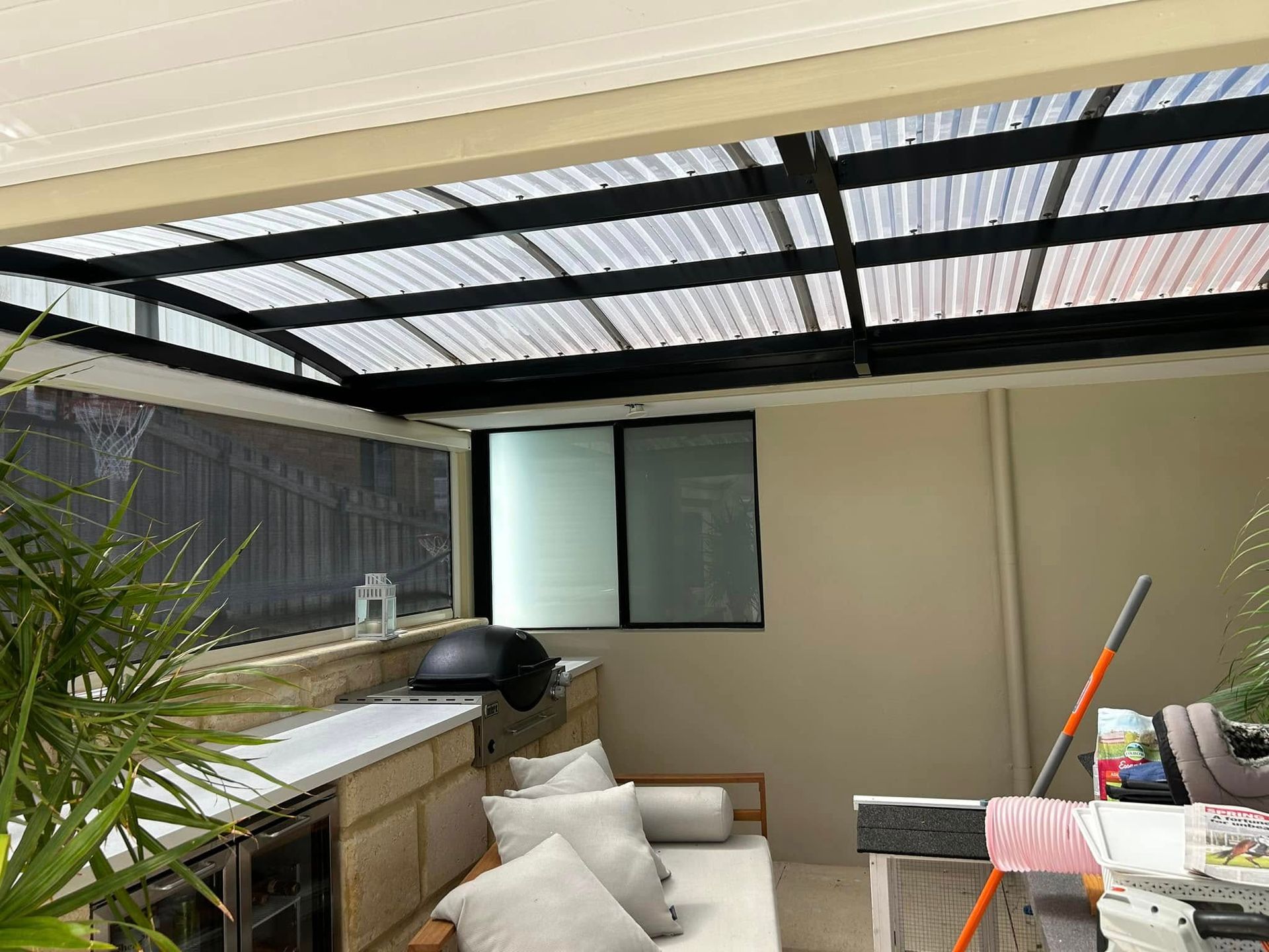 Covered patio with a sink, bench seating, and cushions beside a window and sliding door