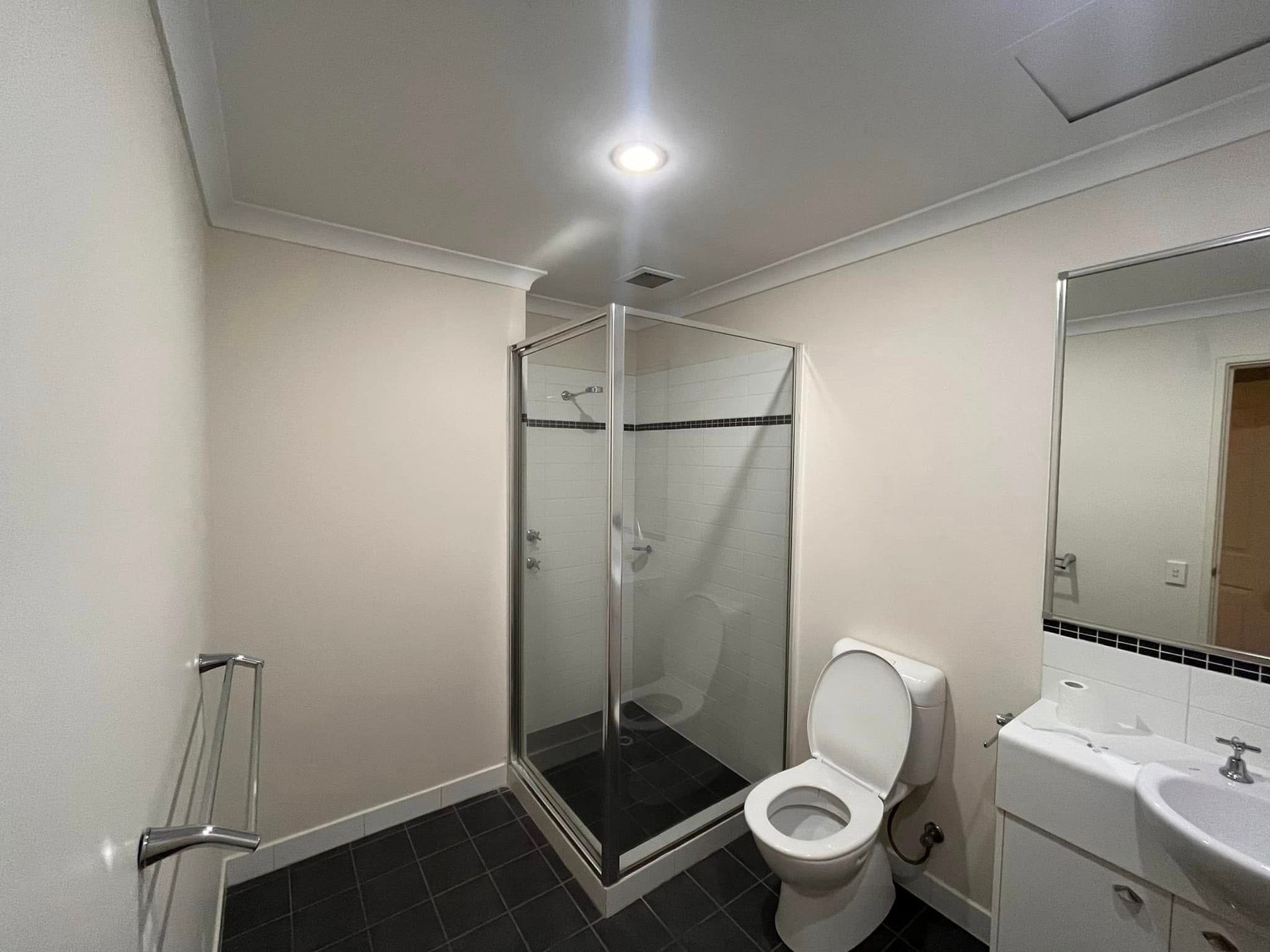 Small bathroom with glass shower, toilet, sink, and wall mirror.